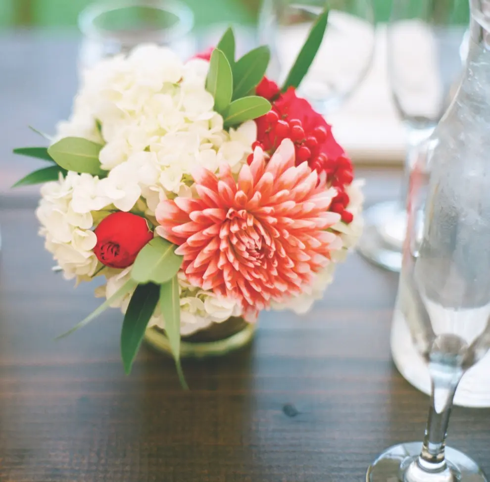 La florista Jackie Reisenauer propone este centro de mesa, en el que la dalia de color coral es la protagonista. Sin complejos, lo combina con rojos, verdes y blancos: para ella, todo vale. La foto es de Laura Ivanova.