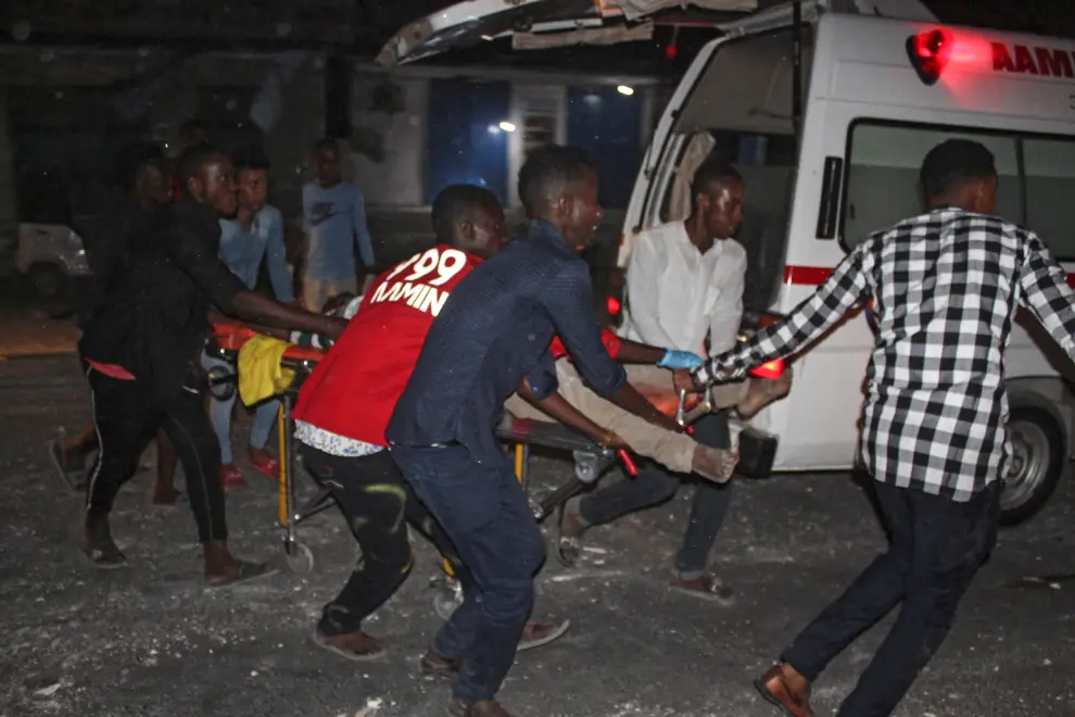 Varias personas trasladan a un herido en el lugar donde explotó un camión bomba este jueves, en Mogadiscio (Somalia).