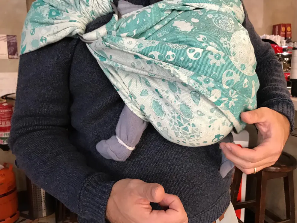 Un papá zaragozano lleva a su pequeño en un portabebés.