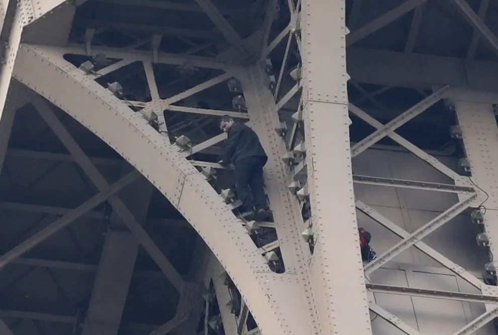 Un hombre escala la Torre Eiffel de París