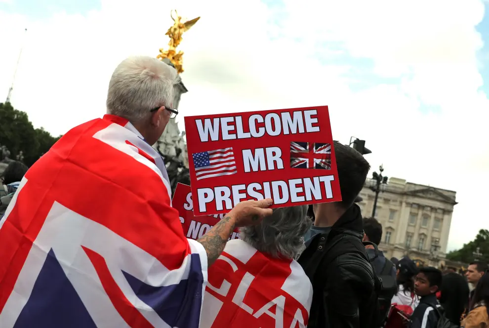 Varias personas esperan la llegada del presidente estadounidense Donald Trump en frente del Buckingham Palace de Londres.