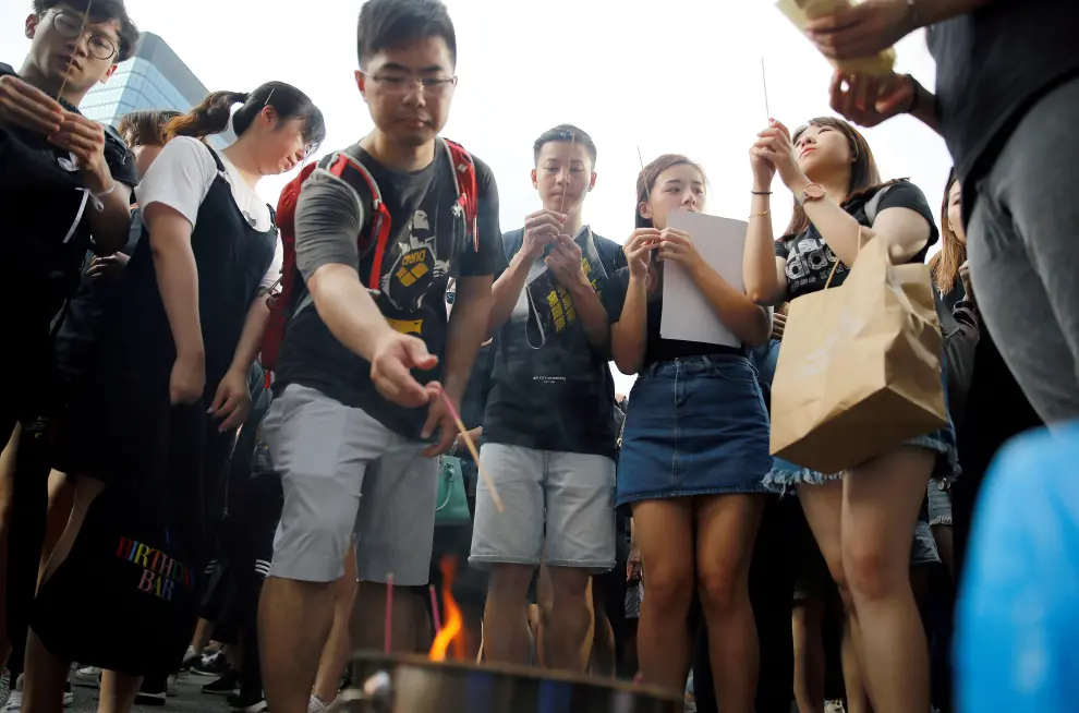 Protesters light incense sticks as they pay honours to a man, who died after falling from a scaffolding at the Pacific Place complex while protesting, during a demonstration demanding Hong Kong's leaders to step down and withdraw the extradition bill, in Hong Kong, China, June 16, 2019. REUTERS/Thomas Peter [[[REUTERS VOCENTO]]] HONGKONG-EXTRADITION/