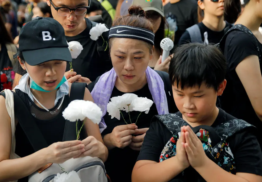 A protester lays paper flowers as she pays honours to a man, who died after falling from a scaffolding at the Pacific Place complex while protesting, during a demonstration demanding Hong Kong's leaders to step down and withdraw the extradition bill, in Hong Kong, China, June 16, 2019. REUTERS/Thomas Peter [[[REUTERS VOCENTO]]] HONGKONG-EXTRADITION/