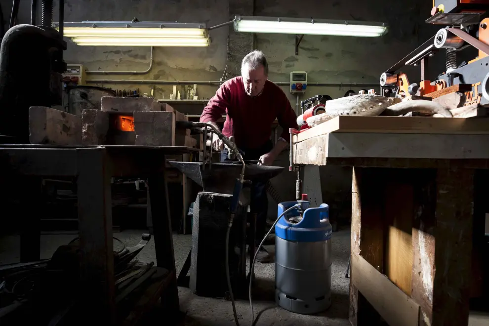 Román Sanz trabaja el acero después de calentarlo en su pequeña estructura de ladrillo, alimentada por dos sopletes en Sástago