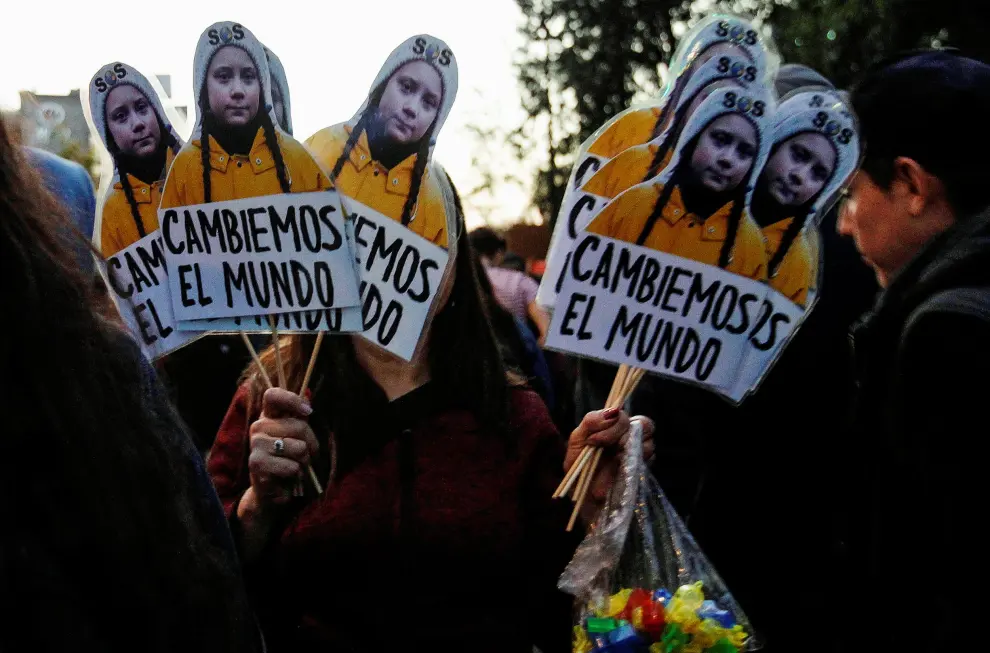Demonstrators take part in a protest against climate change called by the organization Fridays For Future ahead of the 2019 United Nations Climate Change Conference, also known as COP25, in Santiago, Chile, September 27, 2019. A placard with the image of Climate change teen activist Greta Thunberg reads: "Let's change the world". REUTERS/Carlos Vera NO RESALES. NO ARCHIVES [[[REUTERS VOCENTO]]] CLIMATE-CHANGE/STRIKE-CHILE