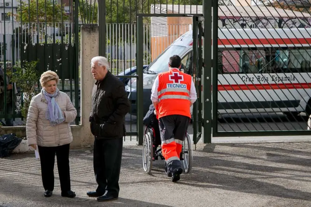 Cecilio Ramos y Natividad de Diego, voluntarios de Cruz Roja, llevan a Tomás Gascón, de 85 años, a su colegio electoral.