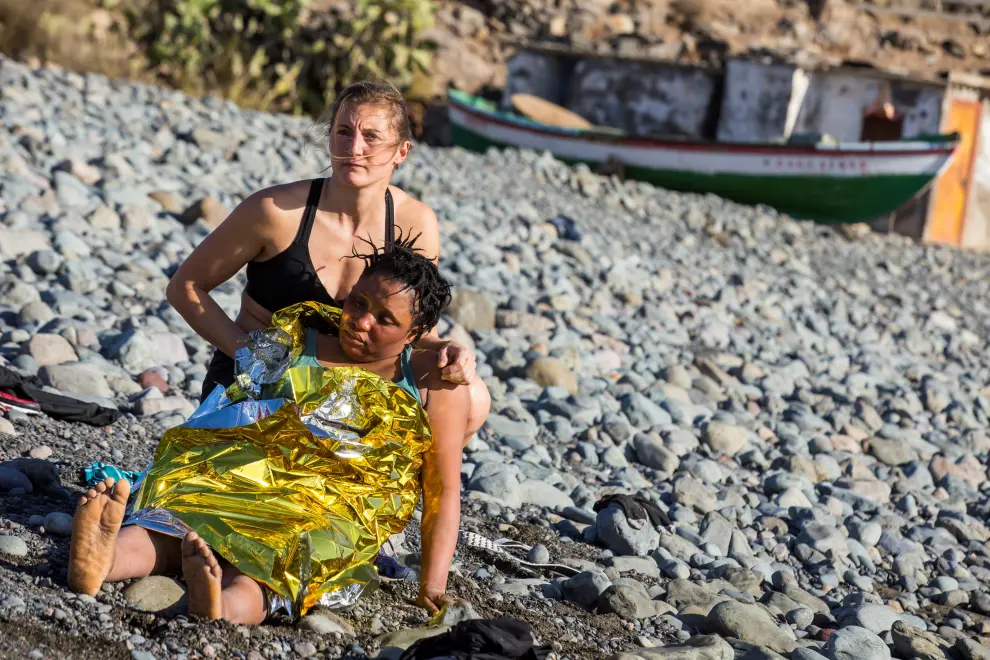 A beachgoer assists a migrant after a group in a dinghy landed on Aguila beach on the island of Gran Canaria, Spain November 29, 2019. REUTERS/Borja Suarez REFILE - CORRECTING LOCATION [[[REUTERS VOCENTO]]] EUROPE-MIGRANTS/SPAIN
