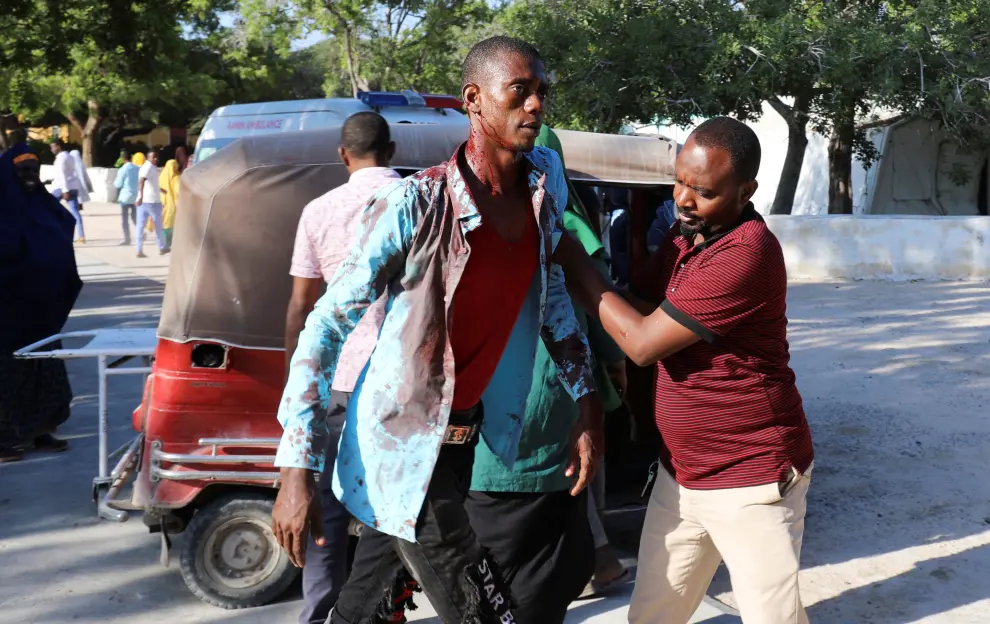 SENSITIVE MATERIAL. THIS IMAGE MAY OFFEND OR DISTURB    A man assists a civilian injured at the scene of a car bomb explosion at a checkpoint in Mogadishu, Somalia  December 28, 2019. REUTERS/Feisal Omar [[[REUTERS VOCENTO]]] SOMALIA-BLAST/