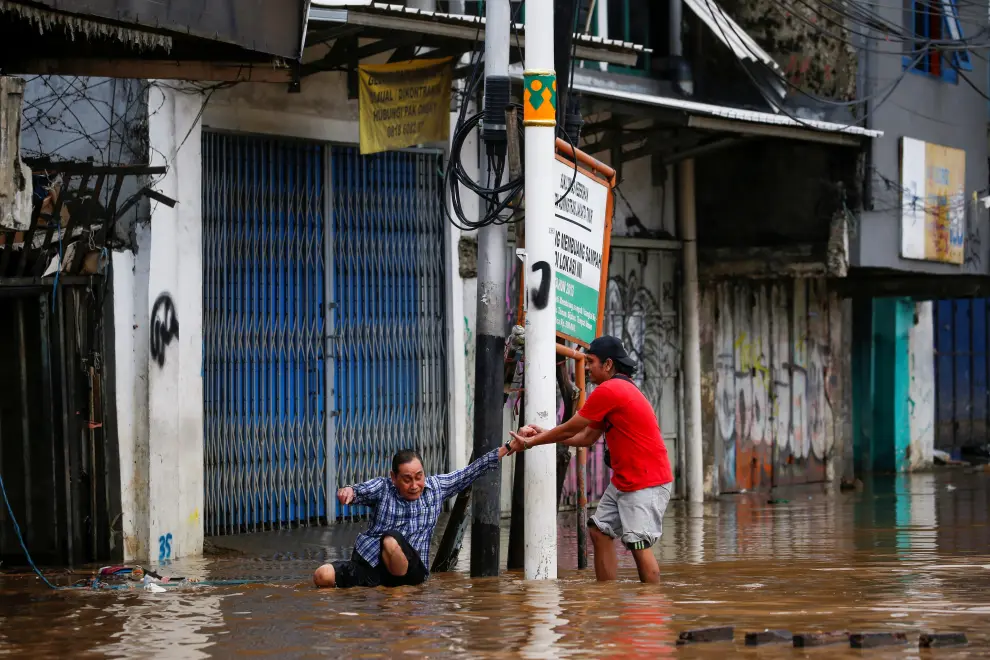 Un hombre mayor es ayudado tras las inundaciones en Yakarta (Indonesia).