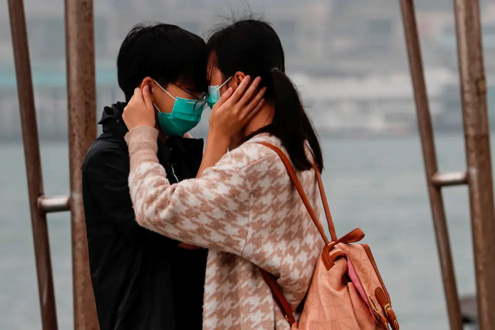 Una pareja con mascarilla se abraza en Hong Kong.