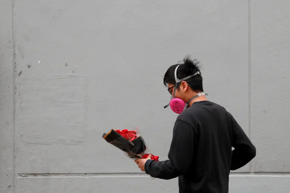 Un hombre con mascarilla lleva un ramo de flores, en una calle de Hong Kong.