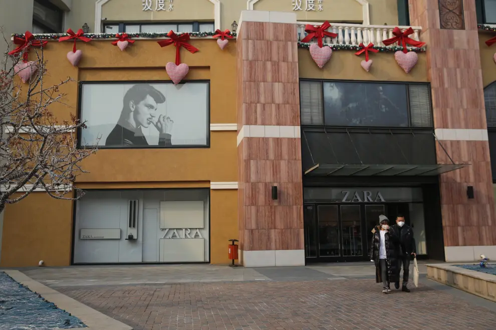 Una pareja con mascarilla protectora pasea por un centro comercial decorado en Pekín.