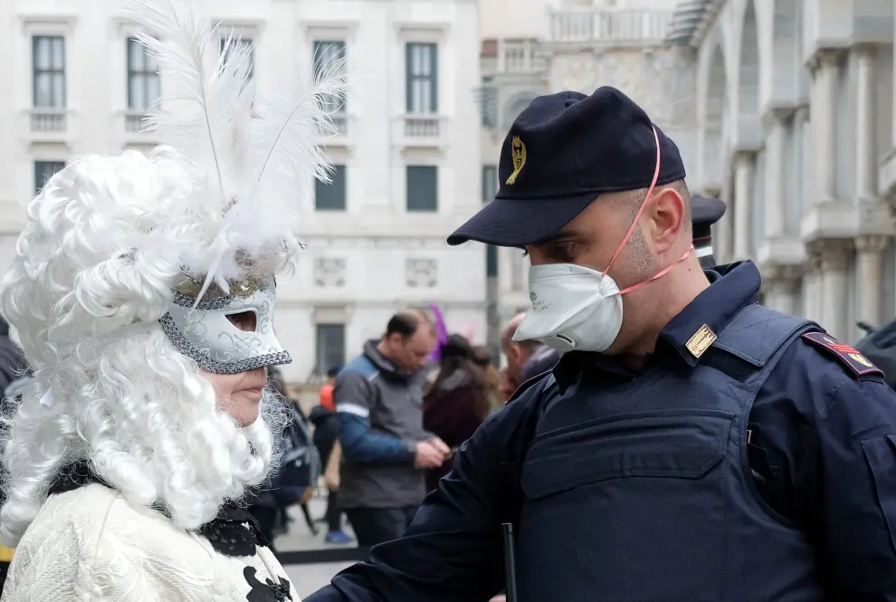 A police officer wearing a protective face mask stands next to a carnival reveller at Venice Carnival, which the last two days of, as well as Sunday night's festivities, have been cancelled because of an outbreak of coronavirus, in Venice, Italy February 23, 2020. REUTERS/Manuel Silvestri [[[REUTERS VOCENTO]]] CHINA-HEALTH/ITALY-VENICE