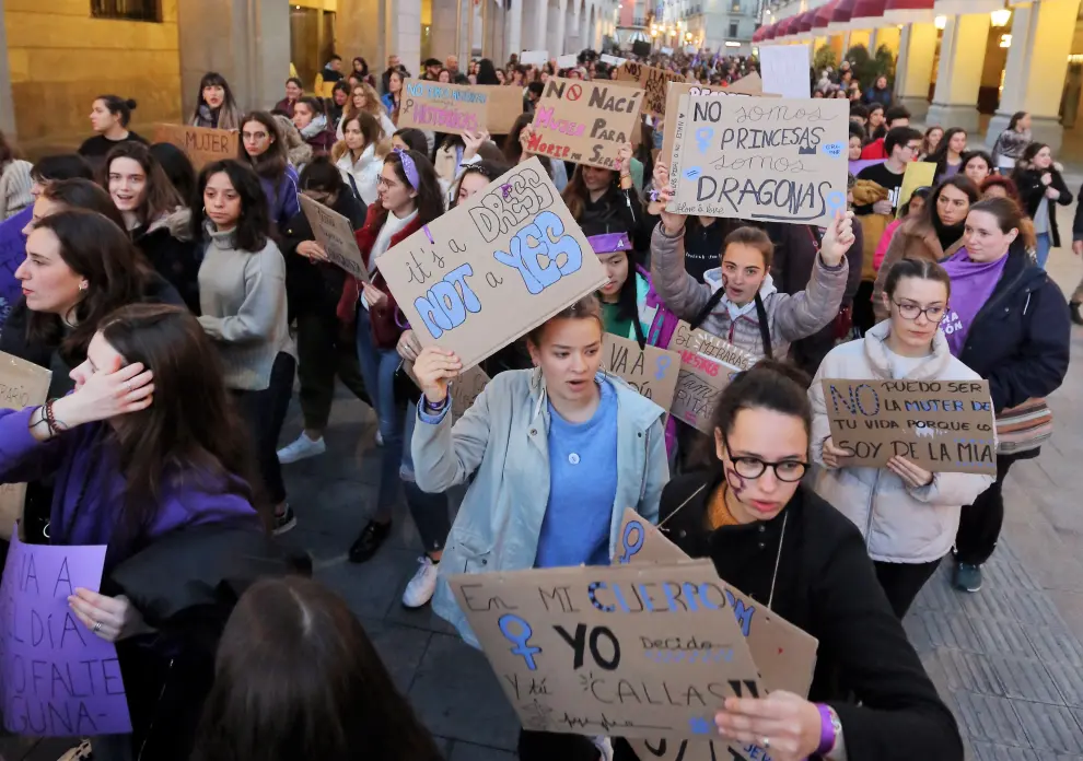 Jóvenes con carteles reivindicativos al paso de la manifestación por los porches de Galicia