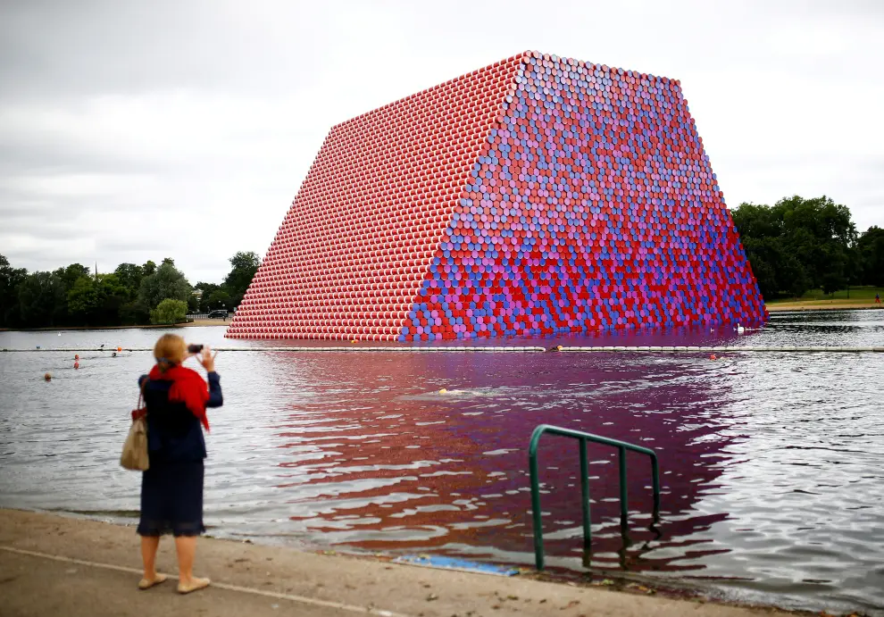 FILE PHOTO: A woman photographs swimmers exercising in the Serpentine River in front of Christo's "The London Mastaba", in Hyde Park, London