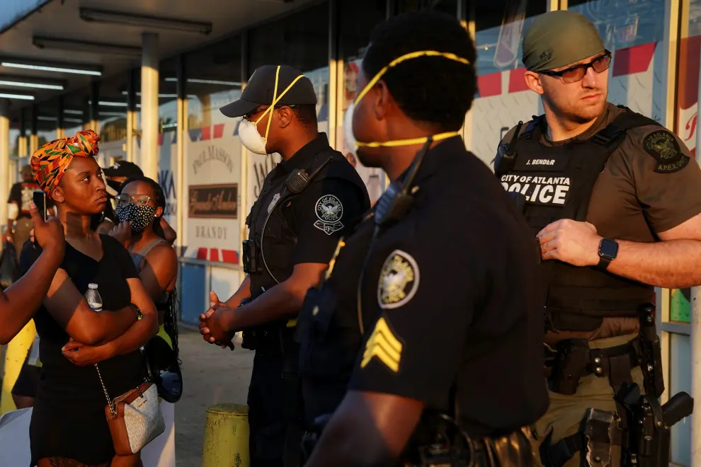Police officers escort a police SUV from a crowd of protesters while bottles of water are thrown at them during a rally against racial inequality and the police shooting death of Rayshard Brooks, in Atlanta, Georgia, U.S. June 13, 2020. REUTERS/Elijah Nouvelage [[[REUTERS VOCENTO]]] MINNEAPOLIS-POLICE/ATLANTA
