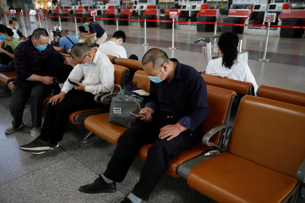 People wearing face masks sit at the departure hall at Beijing Capital International Airport