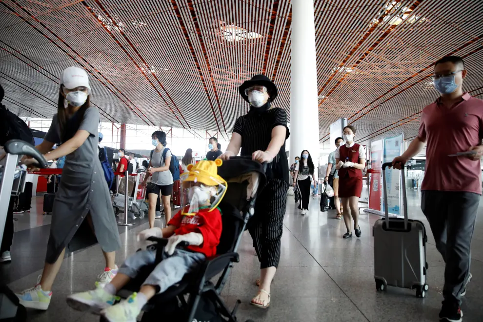 Travellers wearing protective gear are seen at the departure hall of Beijing Capital International Airport