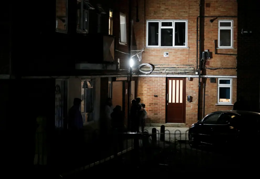 Residents outside a block of flats where suspect was earlier apprehended following reported multiple stabbings in Reading, Britain
