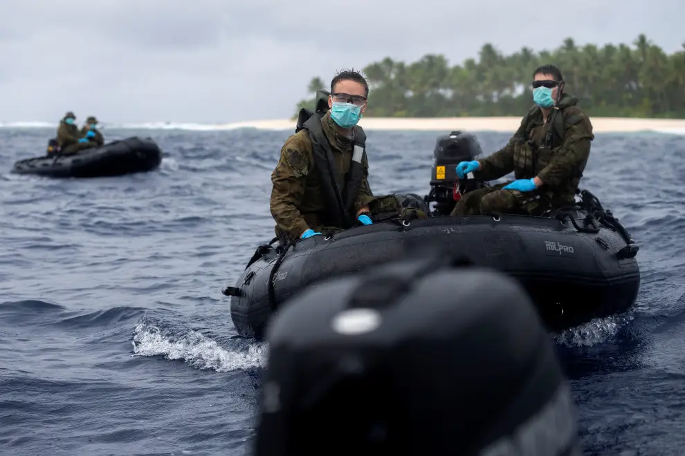 A group of three-stranded mariners from the Federated States of  Micronesia wave goodbye after receiving food and supplies from HMAS Canberra following a search and rescue mission, on Pikelot Island, Micronesia August 3, 2020. Picture taken  August 3, 2020. AUSTRALIAN DEPARTMENT OF DEFENCE/Handout via REUTERS  THIS IMAGE HAS BEEN SUPPLIED BY A THIRD PARTY. NO RESALES. NO ARCHIVES MANDATORY CREDIT [[[REUTERS VOCENTO]]] AUSTRALIA-SAILORS/SOS
