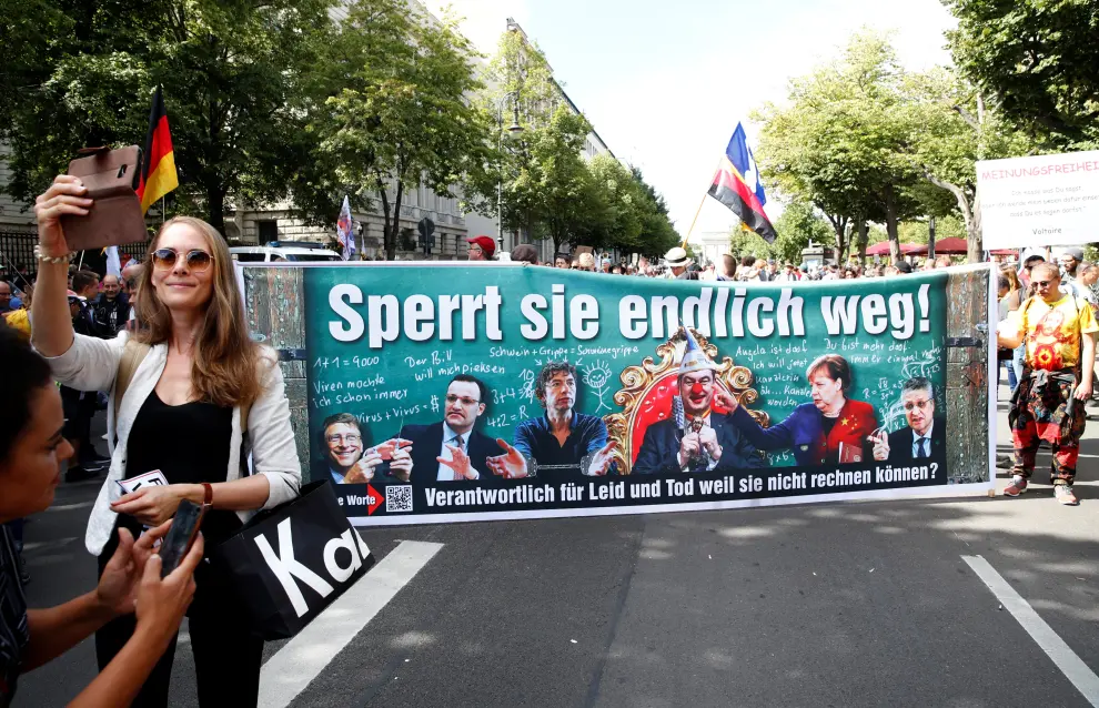 A woman takes a selfie with a banner in the background during a rally against the government's restrictions following the coronavirus disease (COVID-19) outbreak, in Berlin, Germany August 29, 2020. REUTERS/Axel Schmidt [[[REUTERS VOCENTO]]] HEALTH-CORONAVIRUS/GERMANY-PROTEST