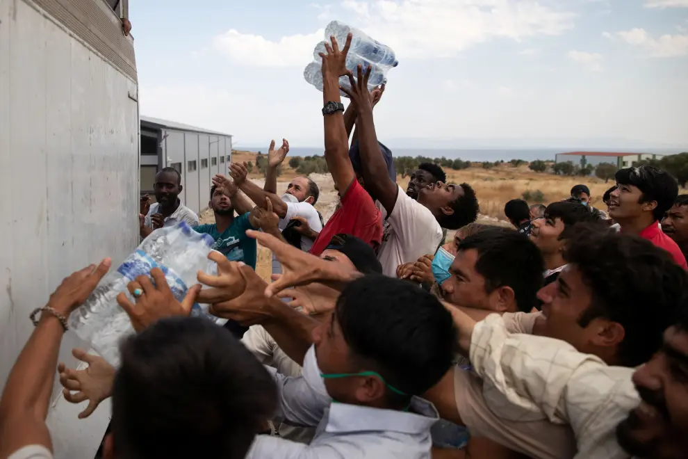 Refugees and migrants from the destroyed Moria camp are handed bottles of water by an NGO, on the island of Lesbos, Greece, September 12, 2020. REUTERS/Alkis Konstantinidis [[[REUTERS VOCENTO]]] EUROPE-MIGRANTS/GREECE-LESBOS