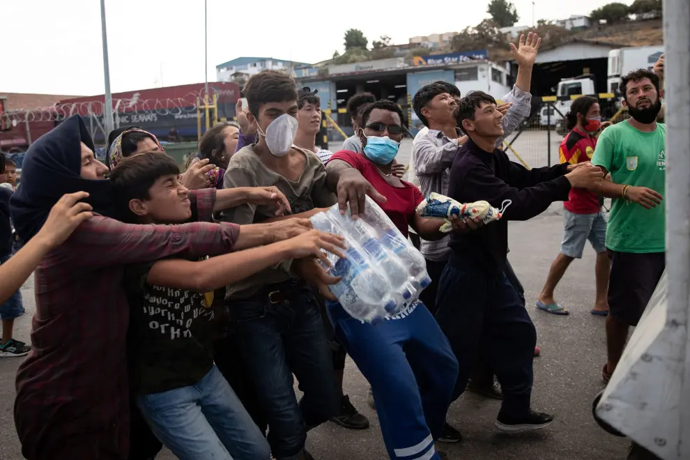 Refugees and migrants from the destroyed Moria camp are handed bottles of water by an NGO, on the island of Lesbos, Greece, September 12, 2020. REUTERS/Alkis Konstantinidis [[[REUTERS VOCENTO]]] EUROPE-MIGRANTS/GREECE-LESBOS