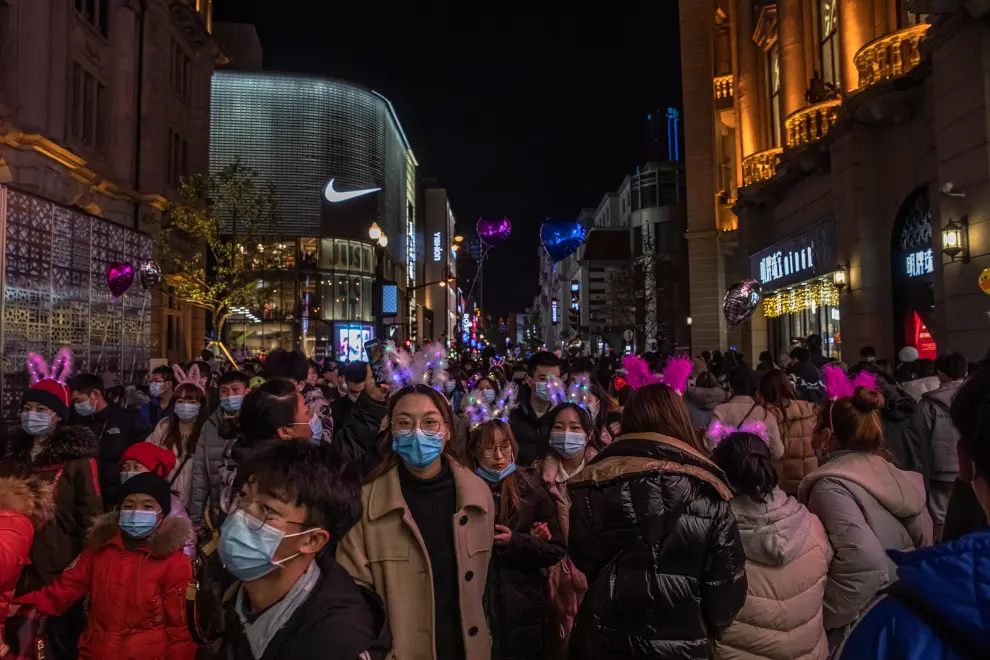 Wuhan (China), 31/12/2020.- People with and without protective masks on their faces walk in a street on New Year's Eve in Wuhan, China, 31 December 2020. Life in Wuhan, a Chinese city of more than 11 million, which nearly a year ago became the epicenter of the coronavirus outbreak is returning to normal. EFE/EPA/ROMAN PILIPEY New Year in Wuhan