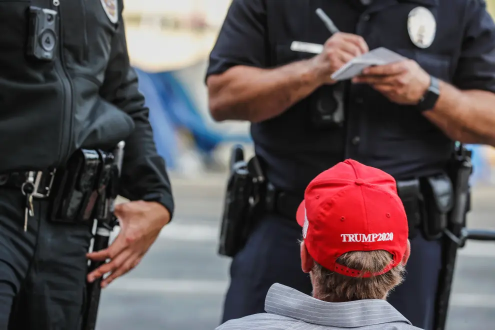 A supporter of U.S. President Donald Trump wearing a Make America Great Again (MAGA) hat looks on upon getting detained by the police while protesting in Los Angeles, California