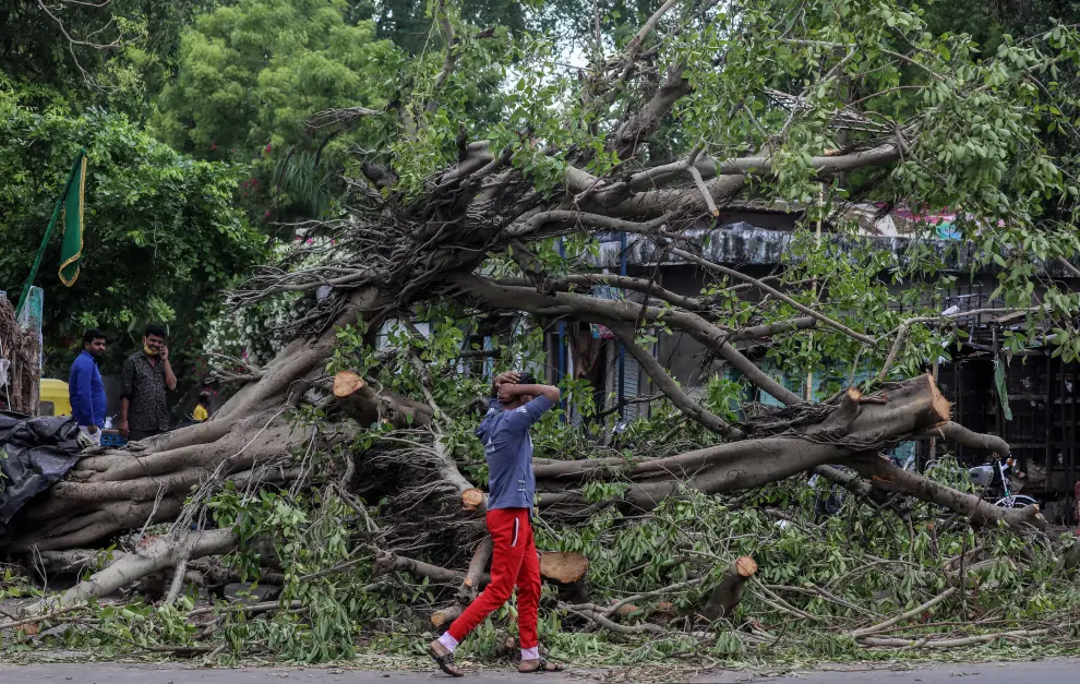Ahmedabad (India), 19/05/2021.- Indian people stand next to the uprooted tree and damaged shops after cyclone Tauktae hit in Ahmedabad, Gujarat, India, 19 May 2021. A powerful cyclone that hit the western coast of India has killed at least 17 people, officials said on 18 May. The intensity of the cyclone Tauktae weakened hours after it made landfall, bringing heavy rains and gusty winds in the western state of Gujarat and its adjoining regions. EFE/EPA/DIVYAKANT SOLANKI Cyclone Tauktae hits Ahmedabad