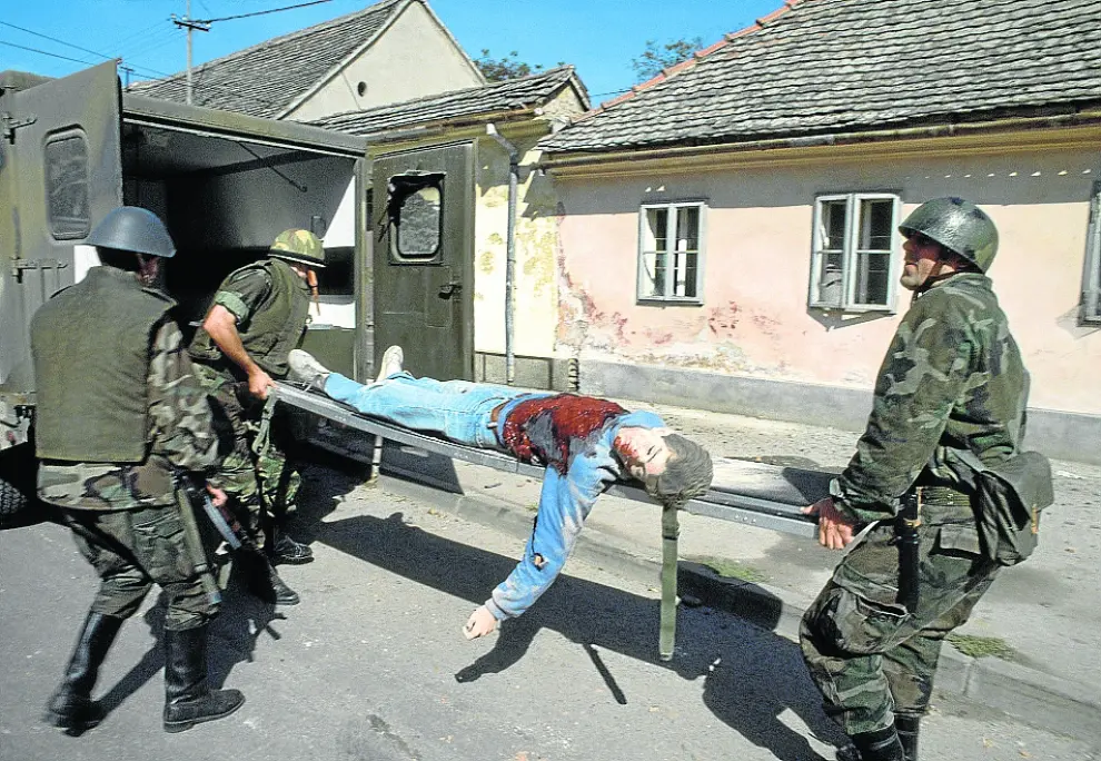 Soldados croatas recogen el cadáver de una víctima en Vinkovci (Croacia).