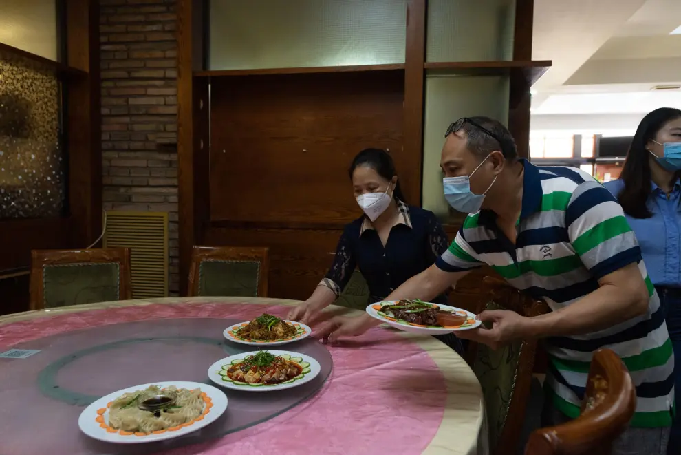 Xianping (en primer término) y Yong sirven platos en su restaurante Kilinke.