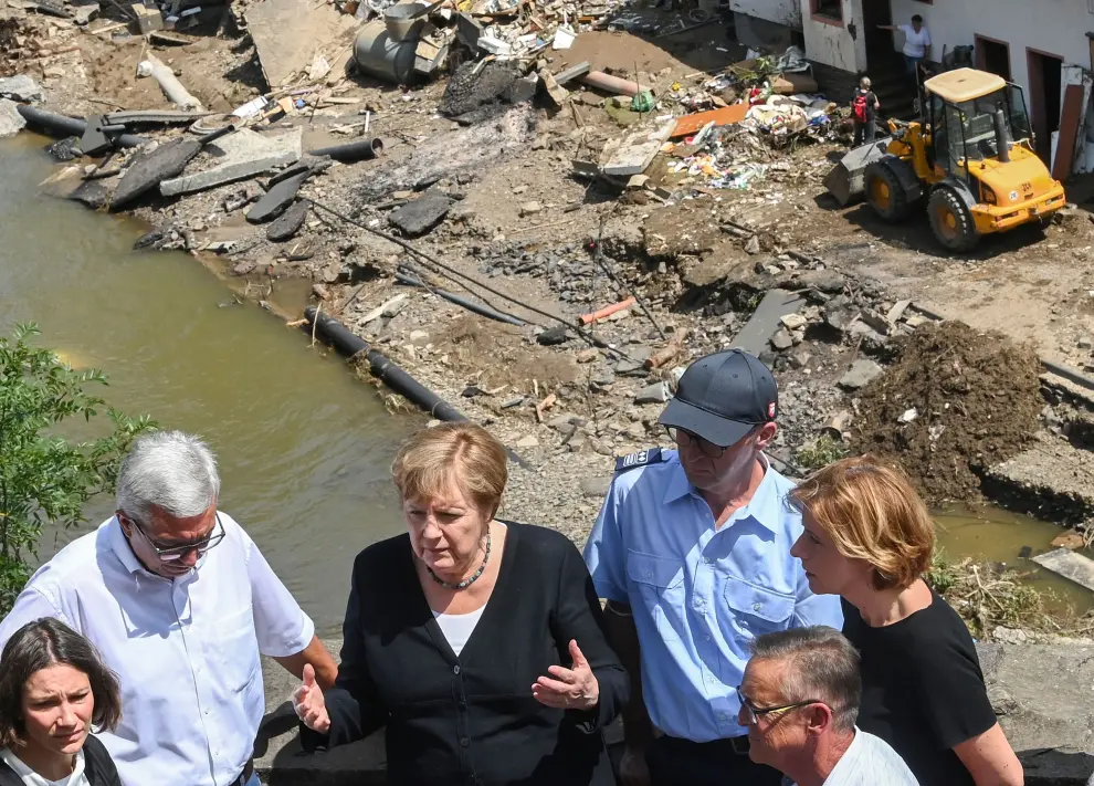 German Chancellor Angela Merkel (L) and Rhineland-Palatinate State Premier Malu Dreyer (3rd L) look up as they stand on a bridge during their visit in the flood-ravaged areas in Schuld near Bad Neuenahr-Ahrweiler, Rhineland-Palatinate state, Germany July 18, 2021. Christof Stache/Pool via REUTERS[[[REUTERS VOCENTO]]] EUROPE-WEATHER/GERMANY MERKEL