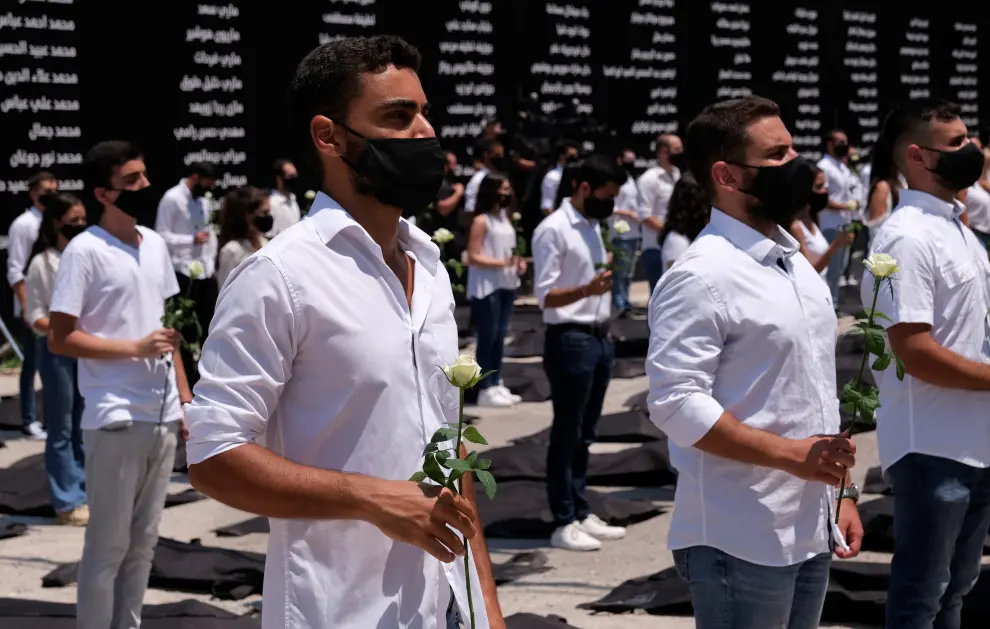 Students affiliated with the Lebanese Forces hold white roses and stand next to body bags in memory of the victims of last years Beirut port blast, as Lebanon marks one-year anniversary of the explosion in Beirut, Lebanon August 4, 2021.  REUTERS/Emilie Madi[[[REUTERS VOCENTO]]] LEBANON-BLAST/ANNIVERSARY