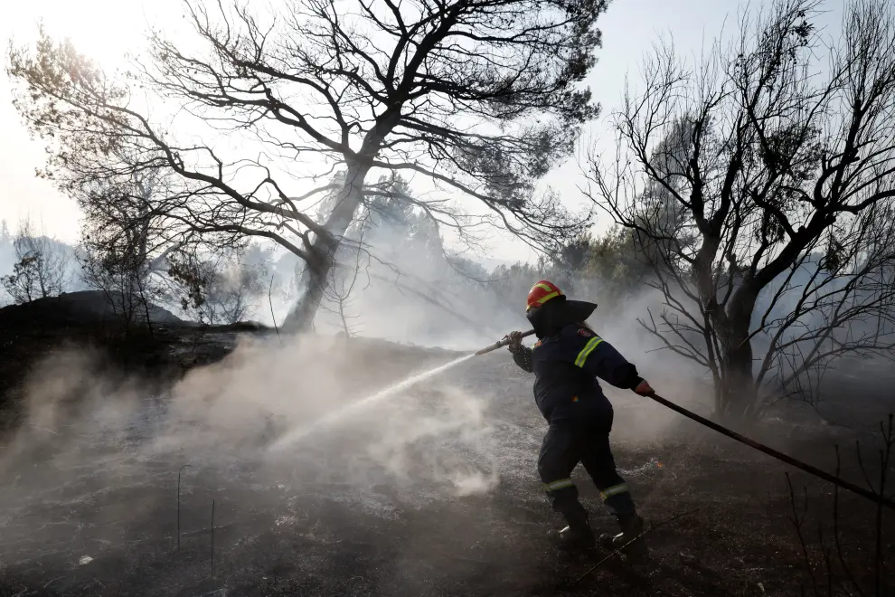 A firefighter sprays water in an attempt to help fight a wildfire at Varympompi suburb north of Athens, Greece, August 4, 2021. REUTERS/Costas Baltas     TPX IMAGES OF THE DAY[[[REUTERS VOCENTO]]] EUROPE-WEATHER/GREECE-WILDFIRES