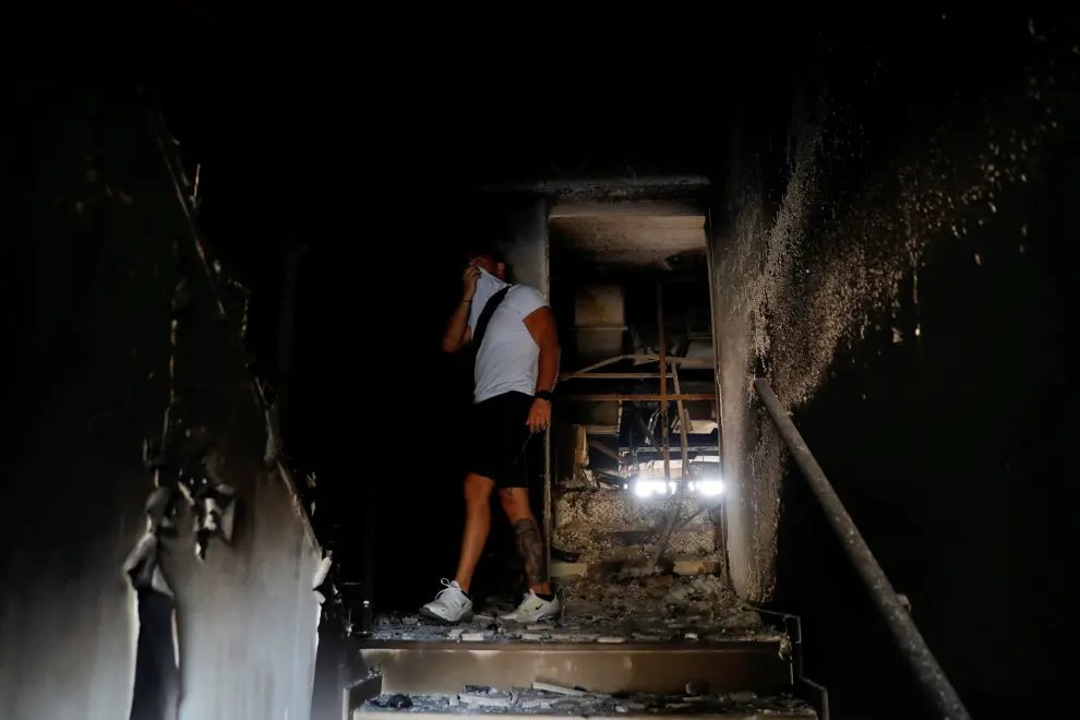 A man walks inside a burnt house following a wildfire at Varympompi suburb north of Athens, Greece, August 4, 2021. REUTERS/Costas Baltas     TPX IMAGES OF THE DAY[[[REUTERS VOCENTO]]] EUROPE-WEATHER/GREECE-WILDFIRES