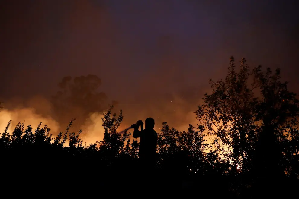A firefighter tries to extinguish a wildfire at the village of Rovies, on Evia island, Greece, August 4, 2021. REUTERS/Costas Baltas[[[REUTERS VOCENTO]]] EUROPE-WEATHER/GREECE-WILDFIRES