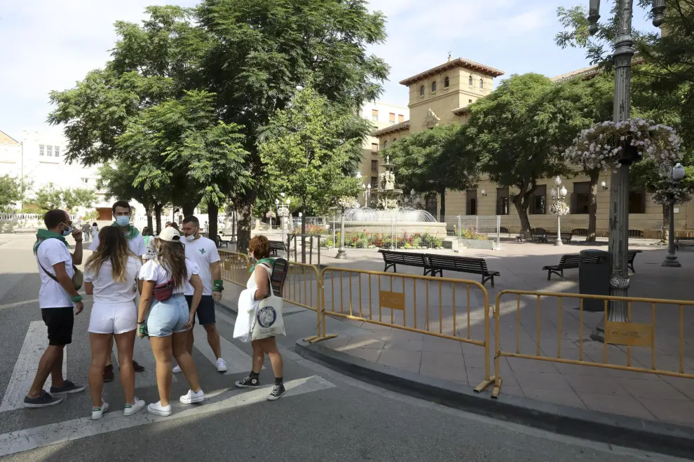 La ciudad de Huesca ha despertado este primer día de las 'no fiestas' de San Lorenzo vestida de blanco y verde, oliendo a albahaca y con la mascarilla como nuevo complemento laurentino.