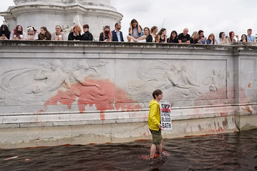 An Extinction Rebellion activist holds a placard and a flare in a fountain during a protest next to Buckingham Palace in London, Britain, August 26, 2021. REUTERS/John Sibley[[[REUTERS VOCENTO]]] CLIMATE-CHANGE/BRITAIN-PROTESTS