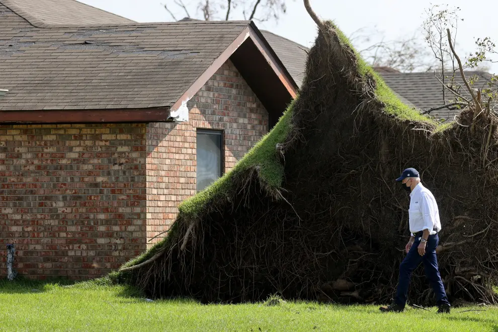 U.S. President Joe Biden walks past an uprooted tree as he tours a neighborhood hit by Hurricane Ida in LaPlace, Louisiana