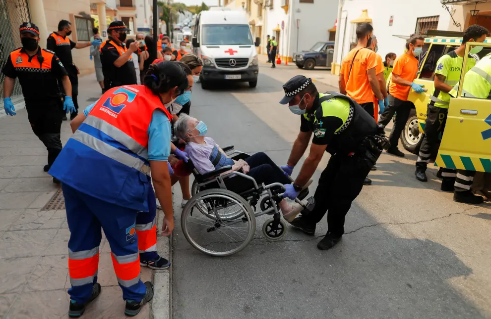 An elderly woman is helped by members of the emergency team as she arrives at a sports center after she was evacuated, due to a wildfire on Sierra Bermeja mountain, in Ronda, near Estepona, Spain, September 12, 2021. REUTERS/Jon Nazca[[[REUTERS VOCENTO]]] CLIMATE-WILDFIRES/SPAIN