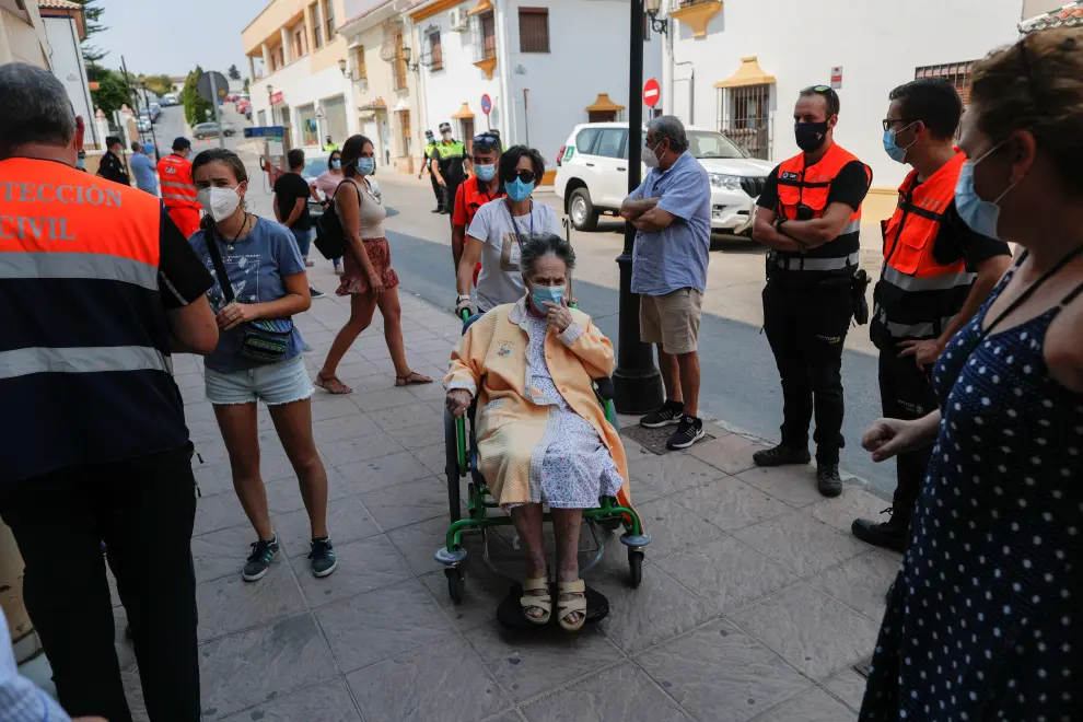 An elderly woman is helped by members of the emergency team as she arrives at a sports center after she was evacuated, due to a wildfire on Sierra Bermeja mountain, in Ronda, near Estepona, Spain, September 12, 2021. REUTERS/Jon Nazca[[[REUTERS VOCENTO]]] CLIMATE-WILDFIRES/SPAIN