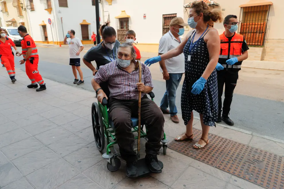 An elderly man is helped by members of the emergency team as he arrives at a sports center after he was evacuated, due to a wildfire on Sierra Bermeja mountain, in Ronda, near Estepona, Spain, September 12, 2021. REUTERS/Jon Nazca[[[REUTERS VOCENTO]]] CLIMATE-WILDFIRES/SPAIN