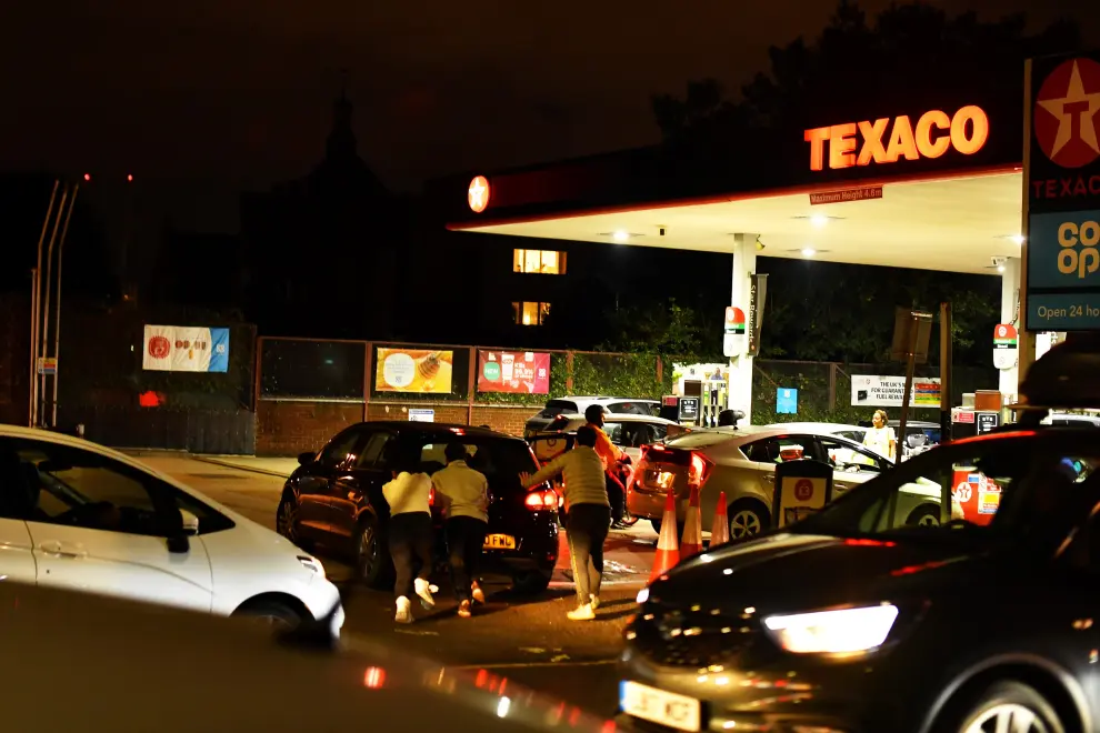 People push as a car, which has run out of petrol, the final few meters on to the forecourt as vehicles queue to refill at a Texaco fuel station in south London, Britain, September 26, 2021. Picture taken September 26, 2021.  REUTERS/Dylan Martinez[[[REUTERS VOCENTO]]] POWER-PRICES/BRITAIN