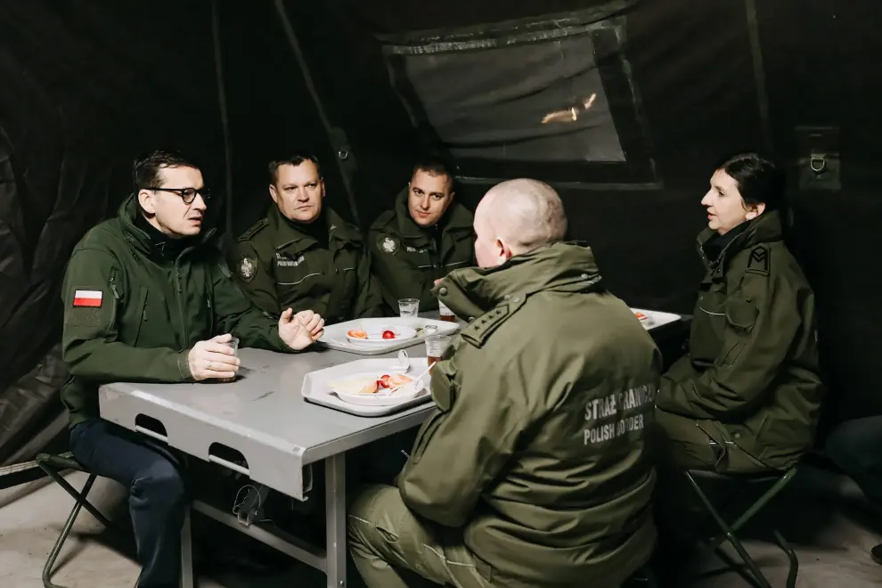 Kuznica (Poland), 09/11/2021.- A handout photo made available by Chancellery of the Prime Minister shows 
Polish prime Minister Mateusz Morawiecki (R) during a meeting with soldiers and officers of the services involved in securing the Polish border with Belarus in the region of Kuznica, eastern-Poland, 09 November 2021. On 08 November morning, the media published information about a large group of migrants planning to cross the Belarusian border with Poland. The Ministry of National Defense informed in the afternoon that the services of the Ministry of Interior and Administration and soldiers had managed to stop the first mass attempt to cross the border. Currently, migrants have set up a camp in the Kuznica region. (Bielorrusia, Polonia) EFE/EPA/ADAM GUZ / CHANCELLERY OF PRIME MINISTER HANDOUT HANDOUT EDITORIAL USE ONLY/NO SALES
 POLAND BELARUS BORDER MIGRATION CRISIS