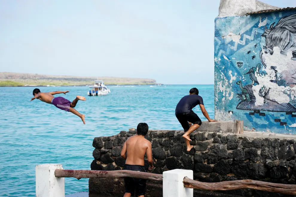 A child jumps into the Pacific ocean after it rose due to a volcanic eruption near Tonga, in Puerto Ayora on the Santa Cruz island of the Galapagos Islands
