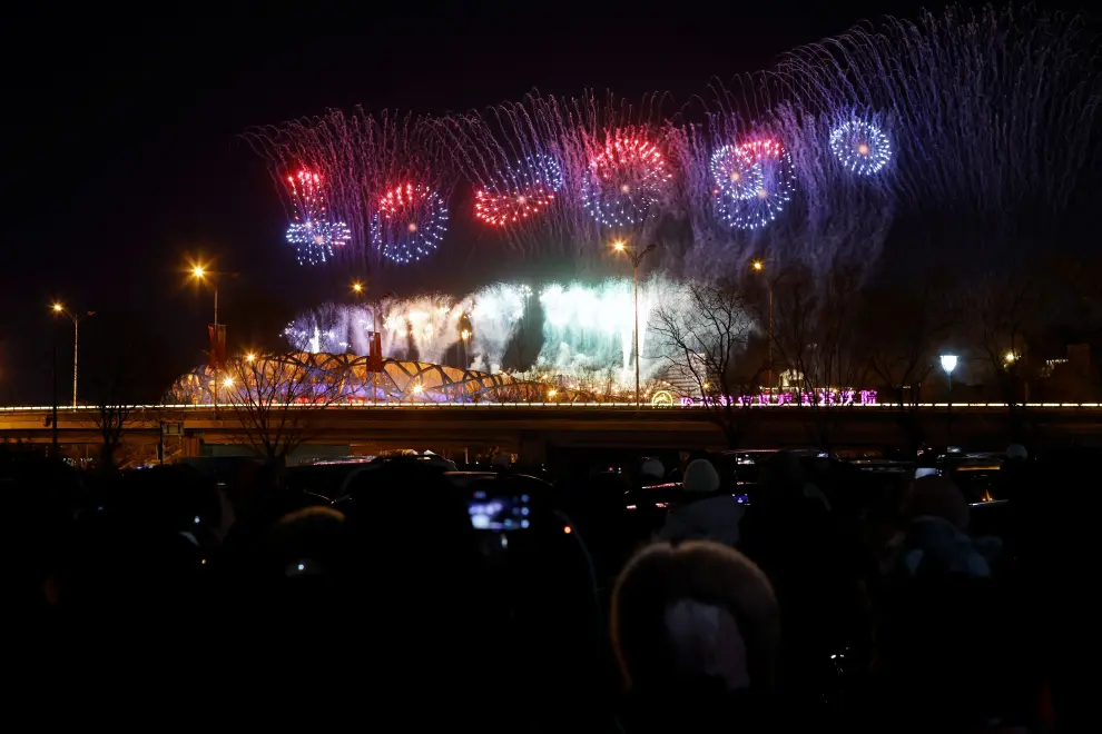 People watch from a parking lot as fireworks explode over the National Stadium, also known as the Bird's Nest, at the end of the closing ceremony of the Beijing 2022 Winter Olympics, in Beijing, China February 20, 2022. REUTERS/Carlos Garcia Rawlins OLYMPICS-2022-CLOSING/