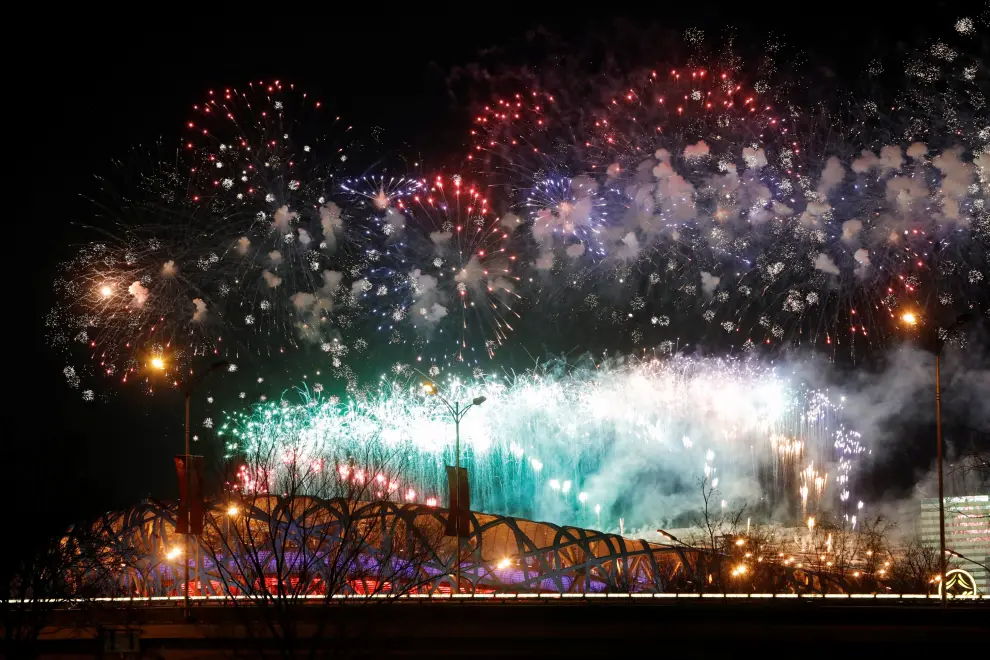People watch from a parking lot as fireworks explode over the National Stadium, also known as the Bird's Nest, at the end of the closing ceremony of the Beijing 2022 Winter Olympics, in Beijing, China February 20, 2022. REUTERS/Carlos Garcia Rawlins OLYMPICS-2022-CLOSING/