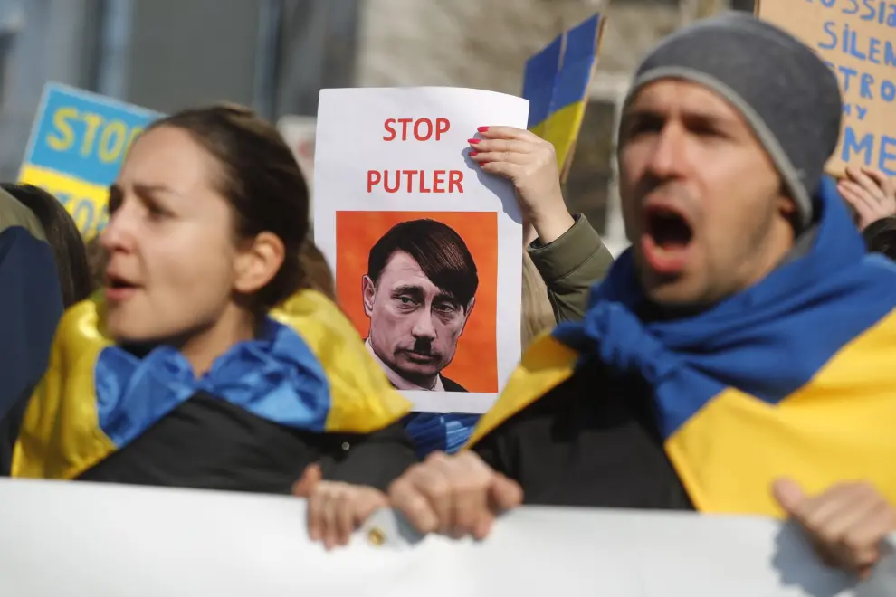 Dos participantes en una protesta en Bélgica contra la guerra sostienen una foto de Putin con bigote pidiendo que pare 'Putler'.