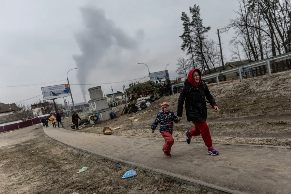 Local residents look for cover as they escape from the town of Irpin, after heavy shelling landed on the only escape route used by locals, while Russian troops advance towards the capital of Kyiv, in Irpin, near Kyiv, Ukraine March 6, 2022. REUTERS/Carlos Barria UKRAINE-CRISIS/IRPIN